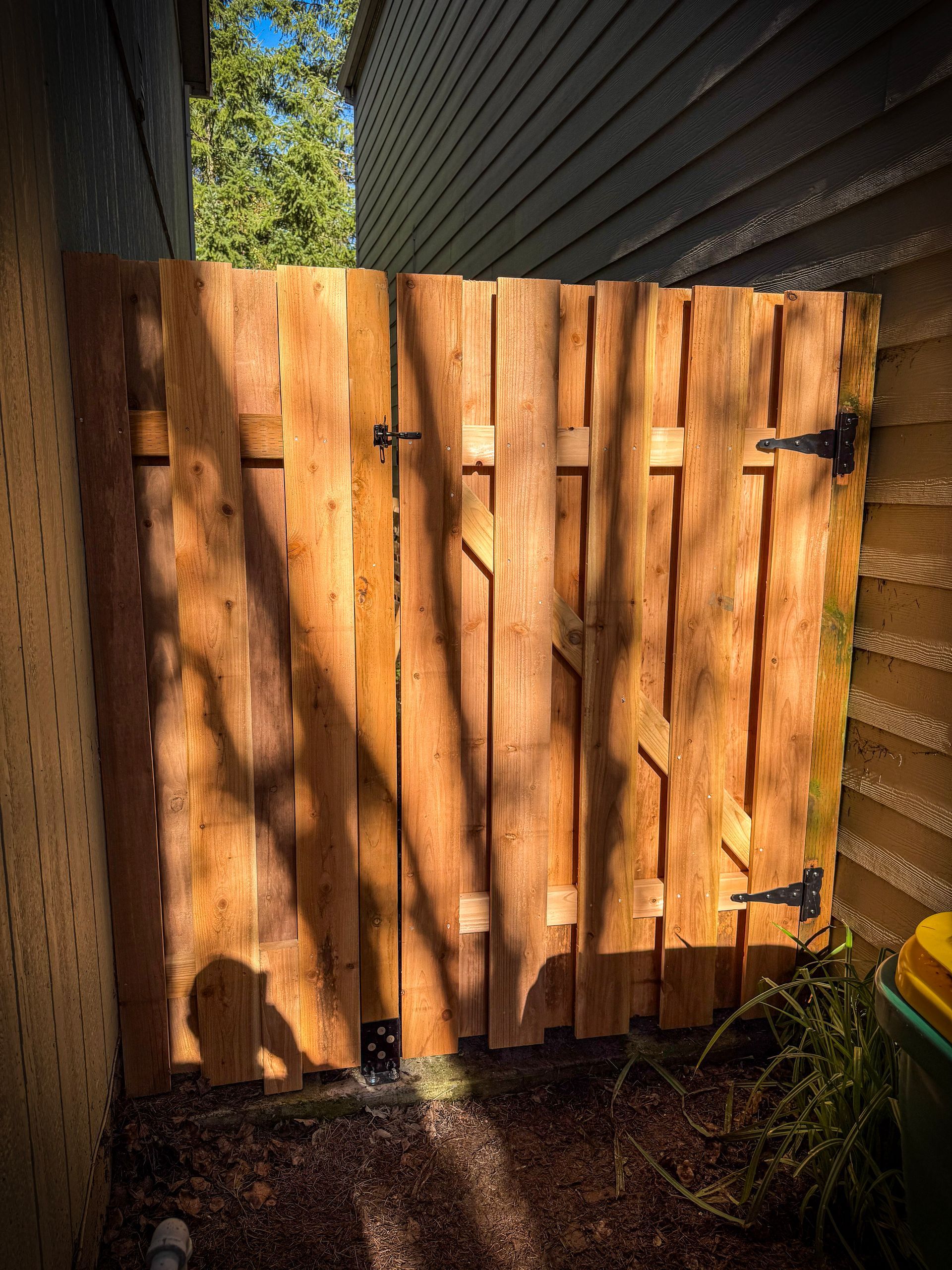 Wooden gate, brown, with black hinges and latch, between beige and tan walls.