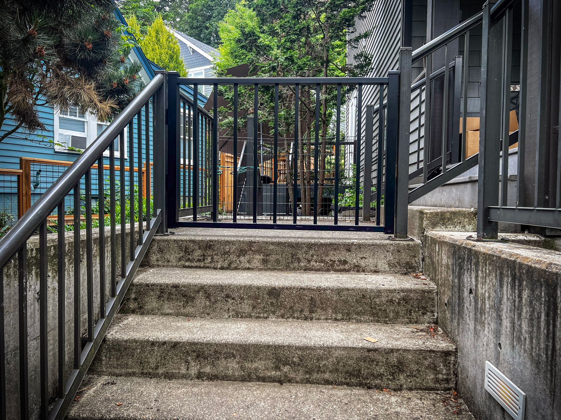 Black chain-link fence with a black top rail, viewed from a close, angled perspective, outdoors.
