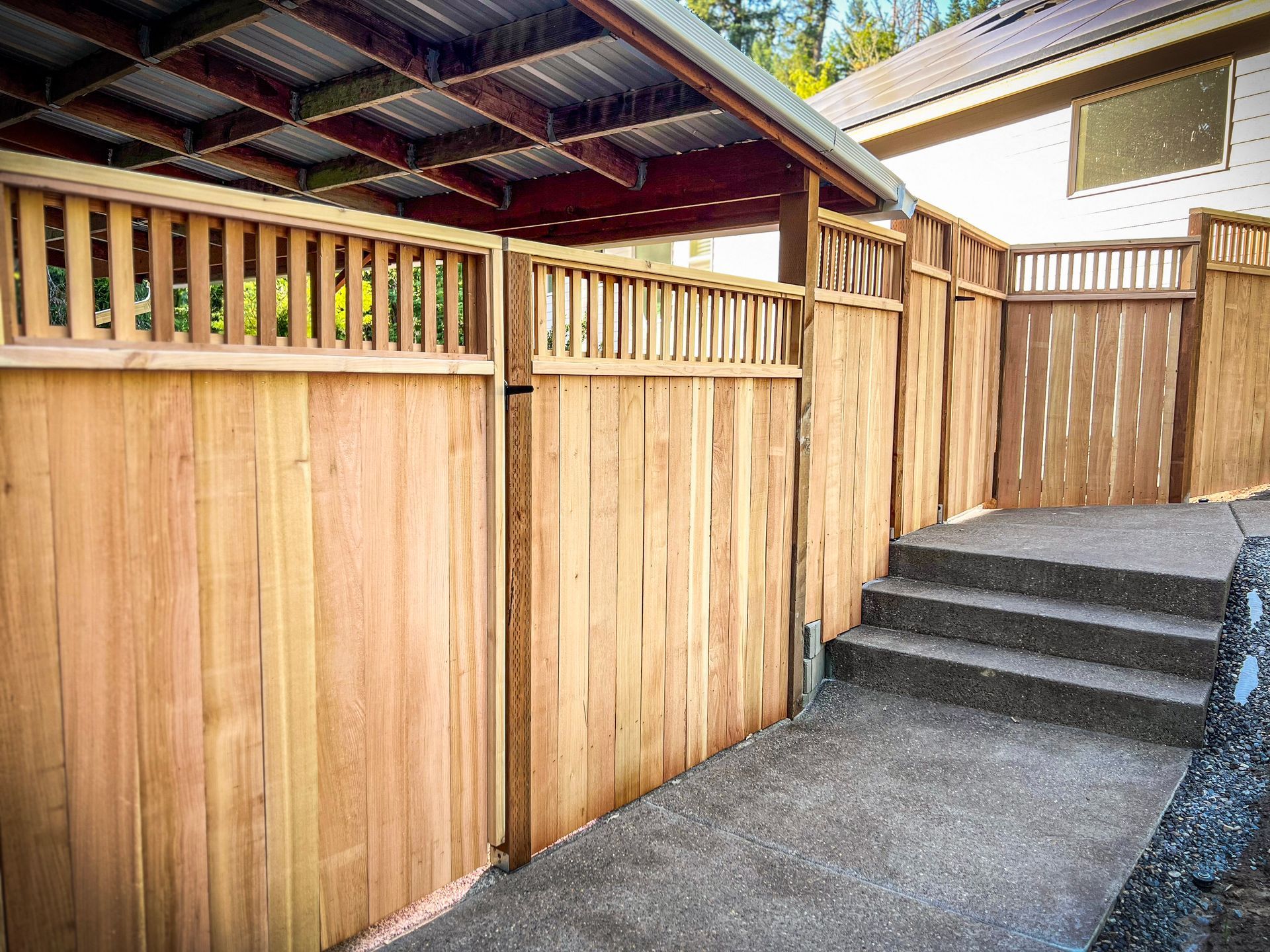 Wooden fence with gate, concrete steps, and a covered walkway.