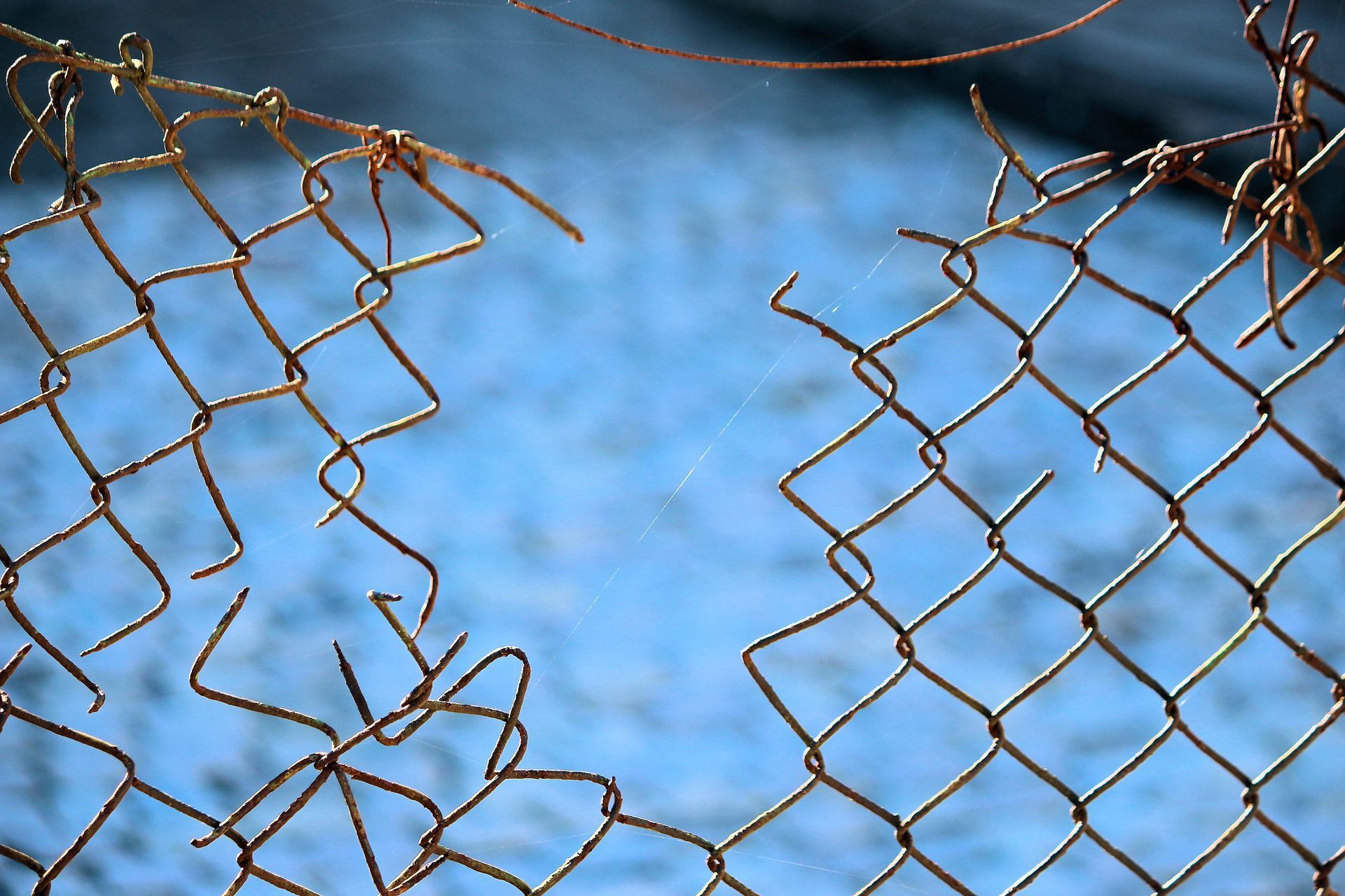 Black chain-link fence with a black top rail, viewed from a close, angled perspective, outdoors.