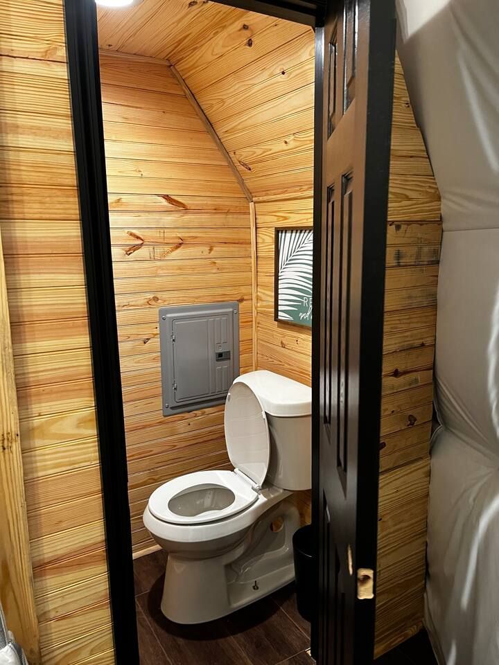 Small bathroom with wooden walls, a toilet, and an open door.