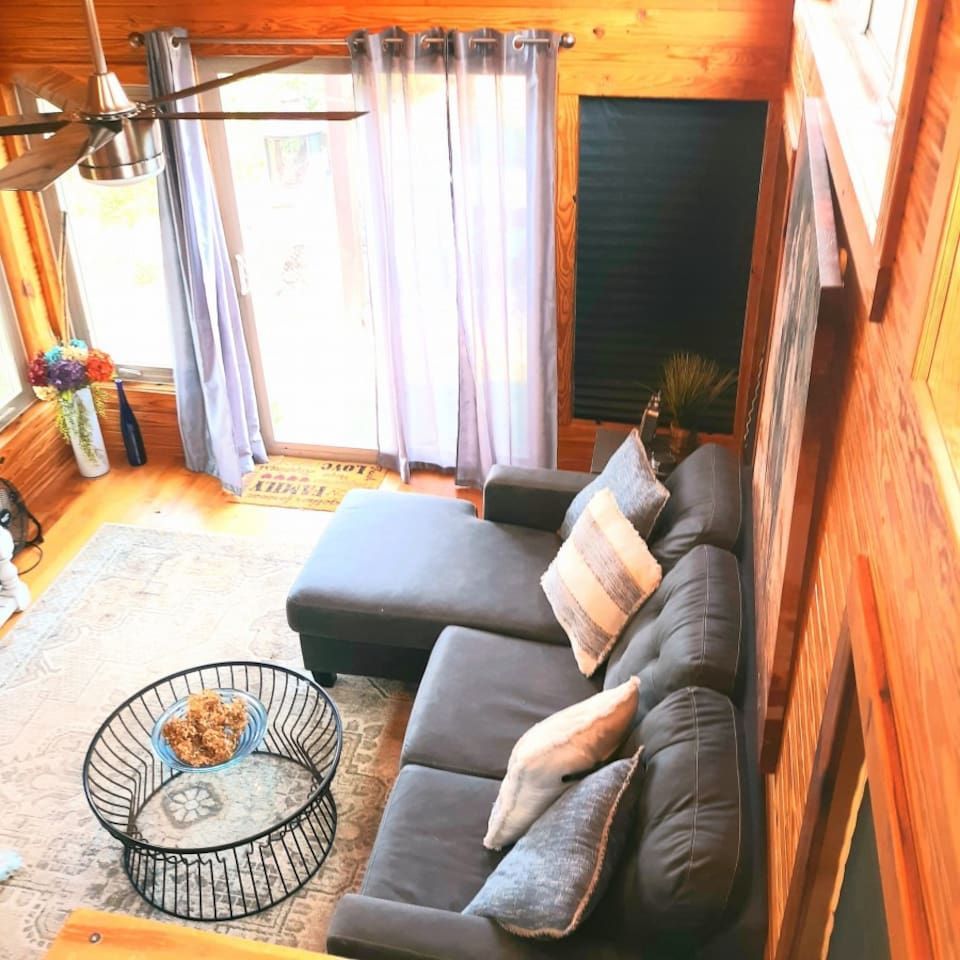 Cozy living room with gray sectional sofa, round glass coffee table, and sliding glass door.