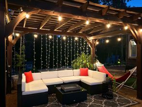 Porch with blue sofa, coffee table, and chairs. Turquoise siding, outdoor setting with trees.