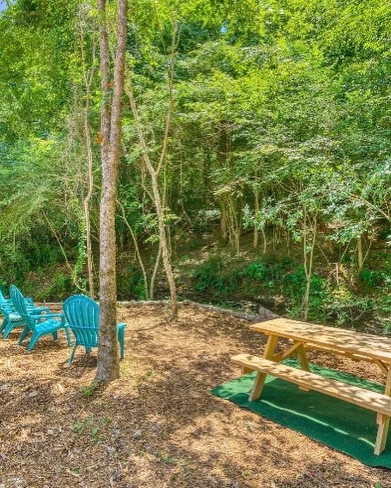 Picnic table and blue chairs in a wooded area.