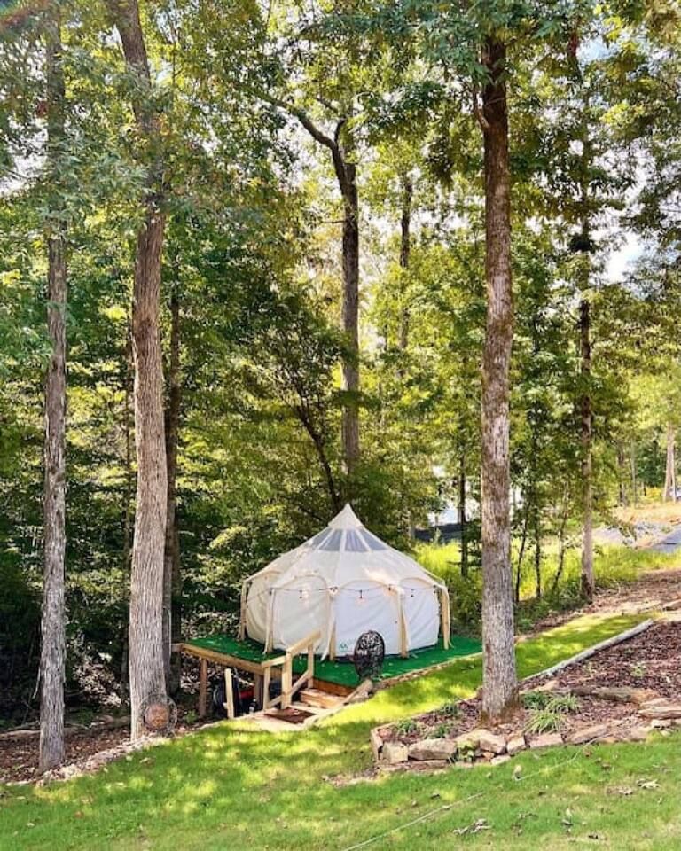 A glamping tent on a wooden platform surrounded by trees.