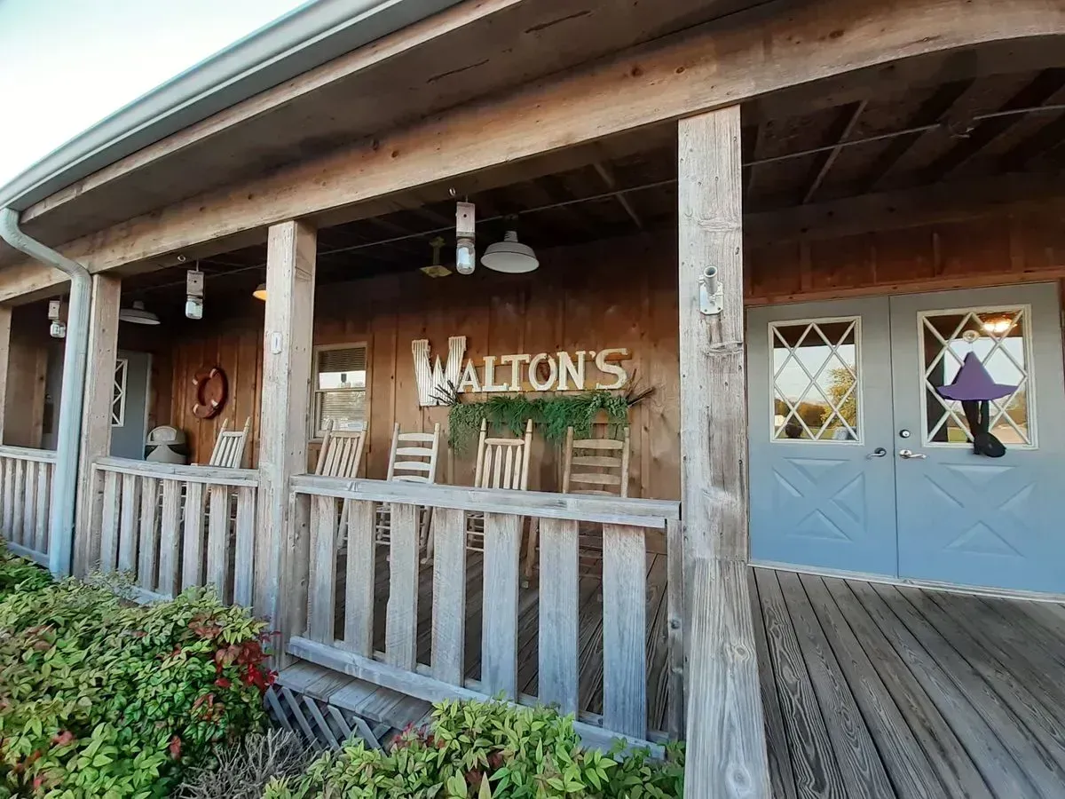 Walton's store exterior with a wooden porch, rocking chairs, and double doors.