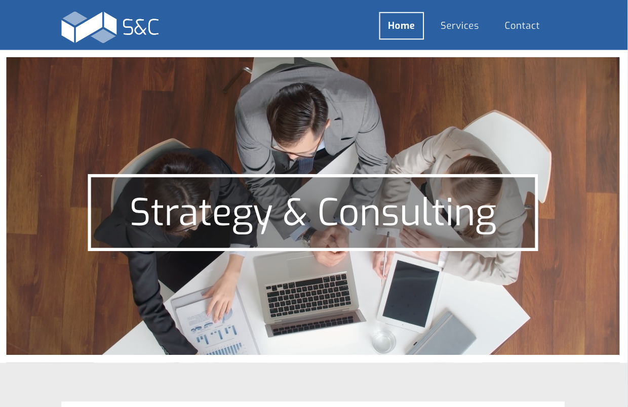 A group of people are sitting around a table with laptops.