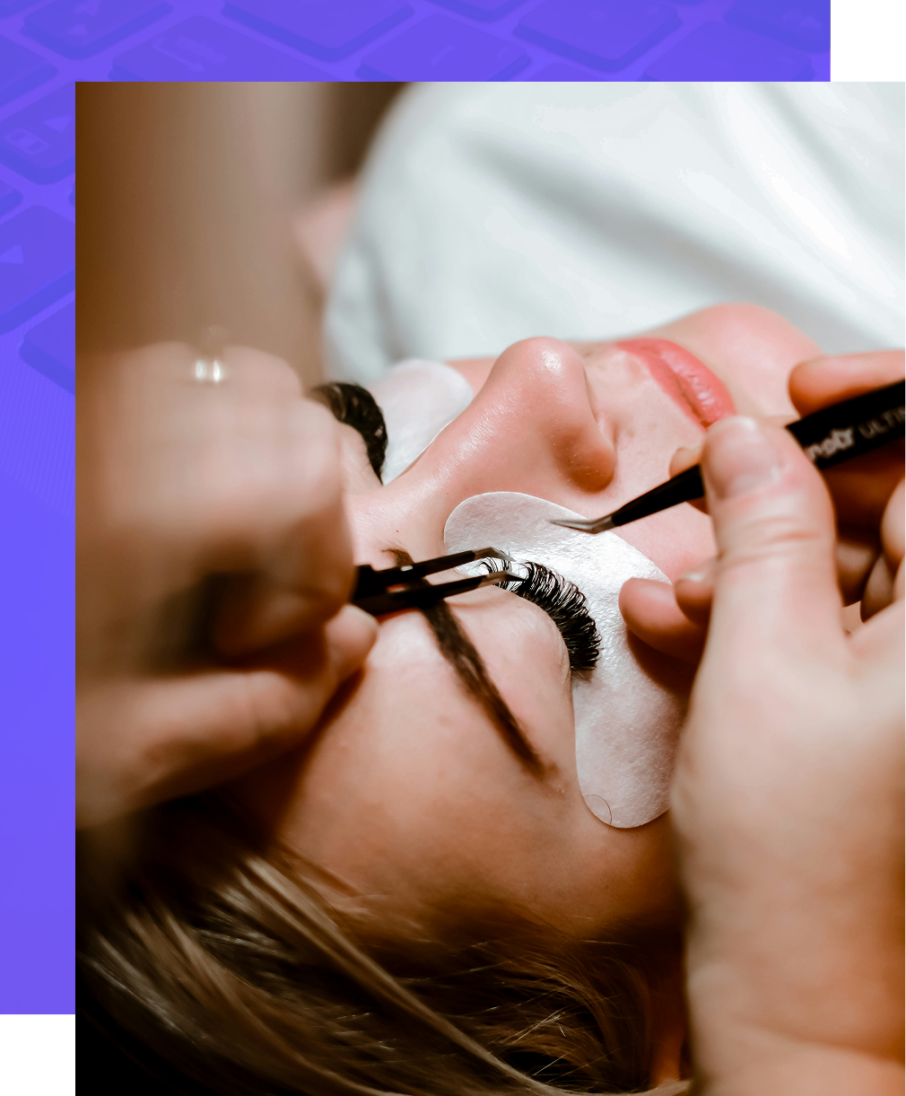 A professional cosmetologist uses tweezers to carefully apply individual eyelash extensions to a client's eye.