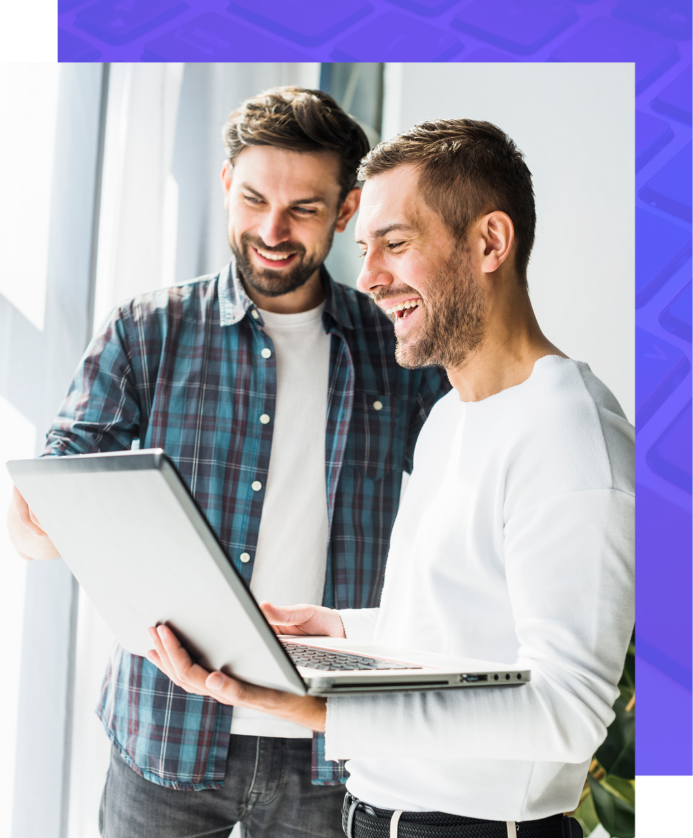 Two people looking at a laptop together and smiling in a bright office space.