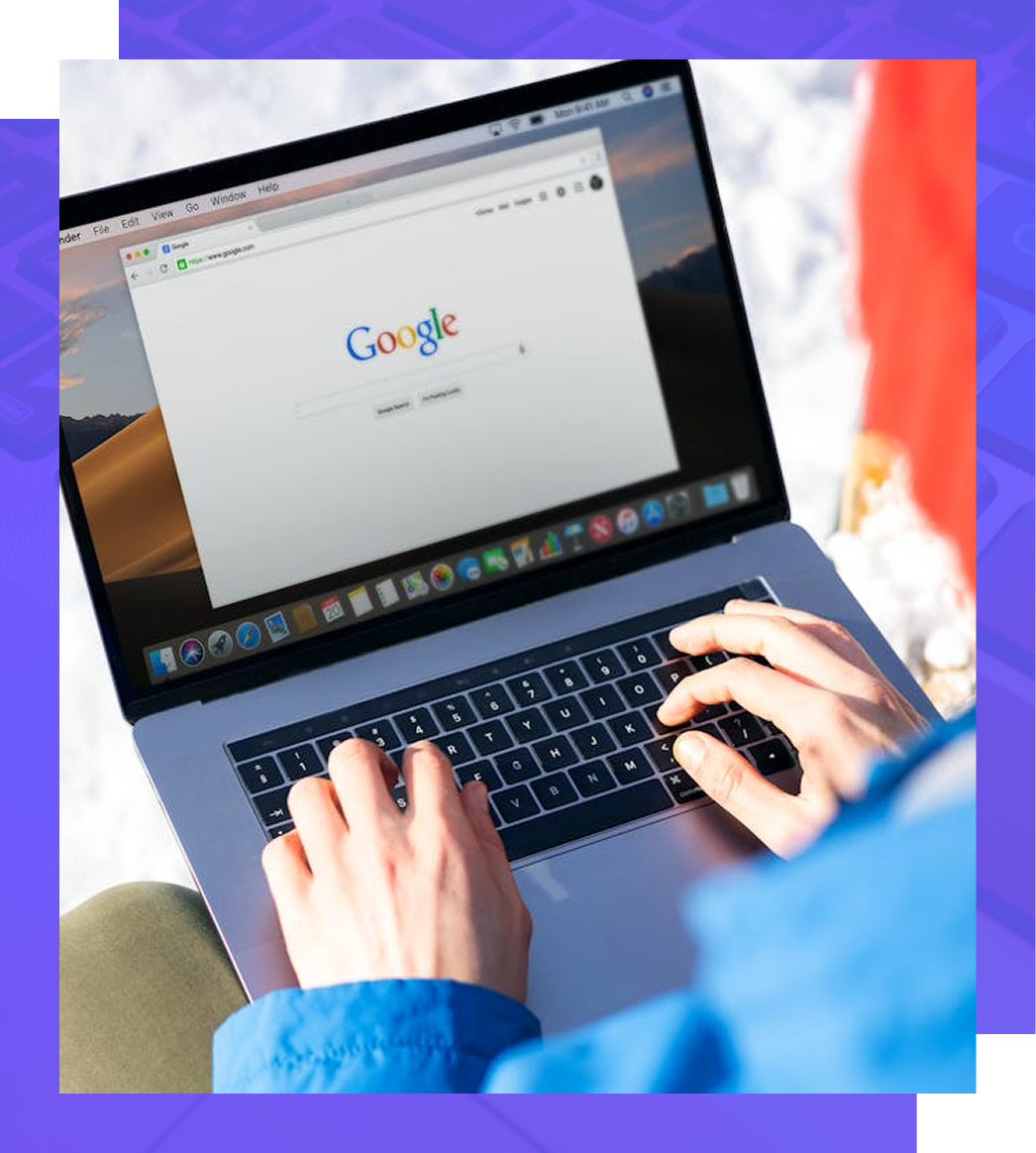 Person typing on a laptop with the Google homepage open, outdoors.