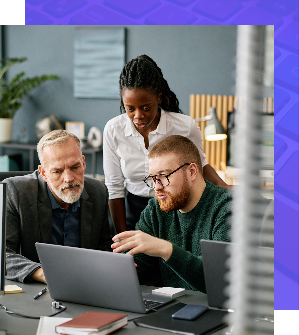 Three people collaborating over a laptop in an office.
