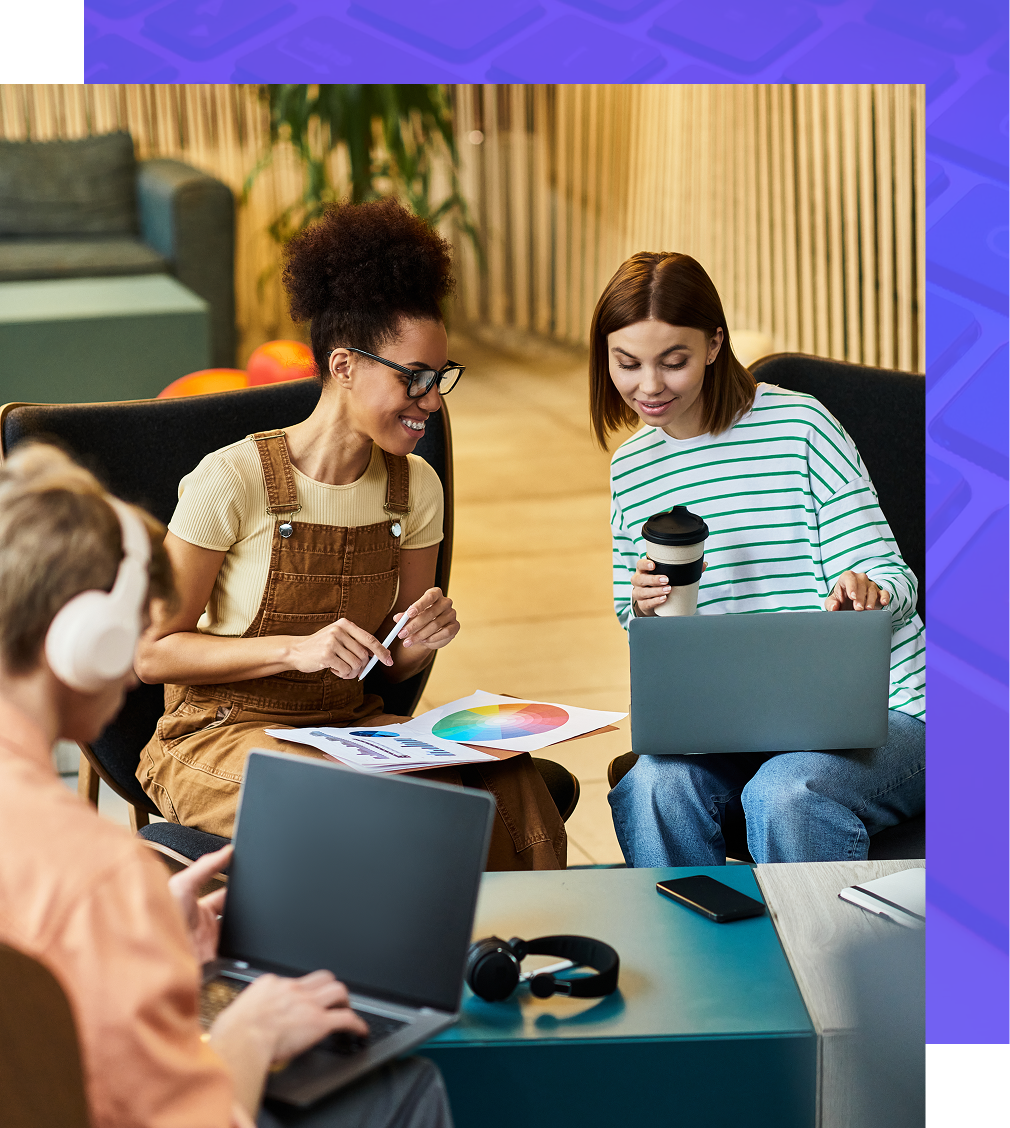Three people working on laptops, one holding a color wheel, in a modern office with seating.
