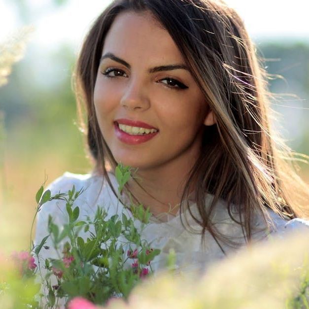 A woman is holding a bouquet of flowers and smiling for the camera.