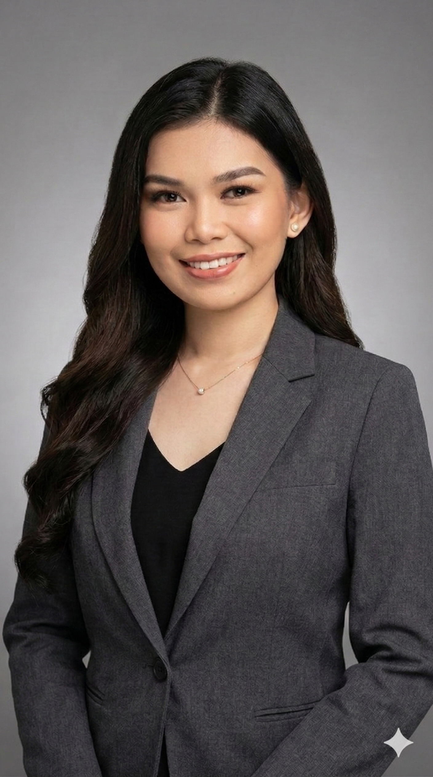 Woman with dark hair smiles, wearing a black blazer over a patterned top.