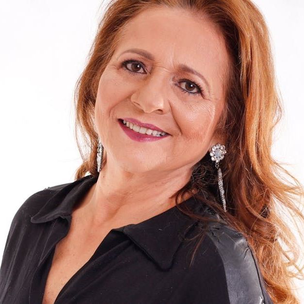 A woman wearing a black shirt and earrings smiles for the camera