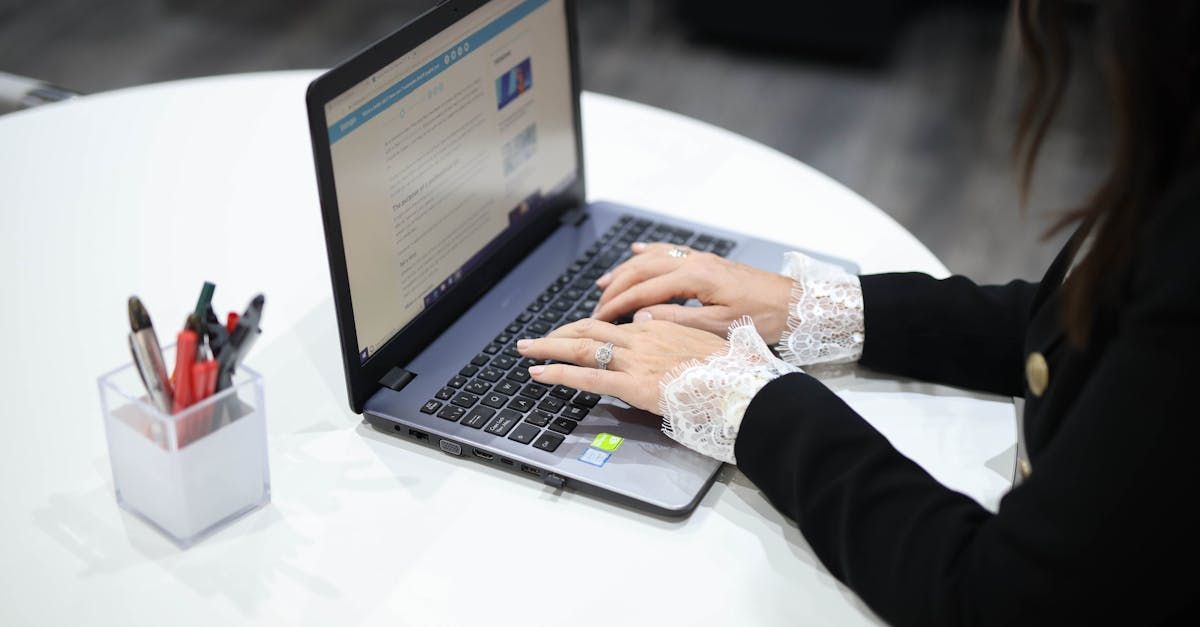 A woman is typing on a laptop computer at a table.