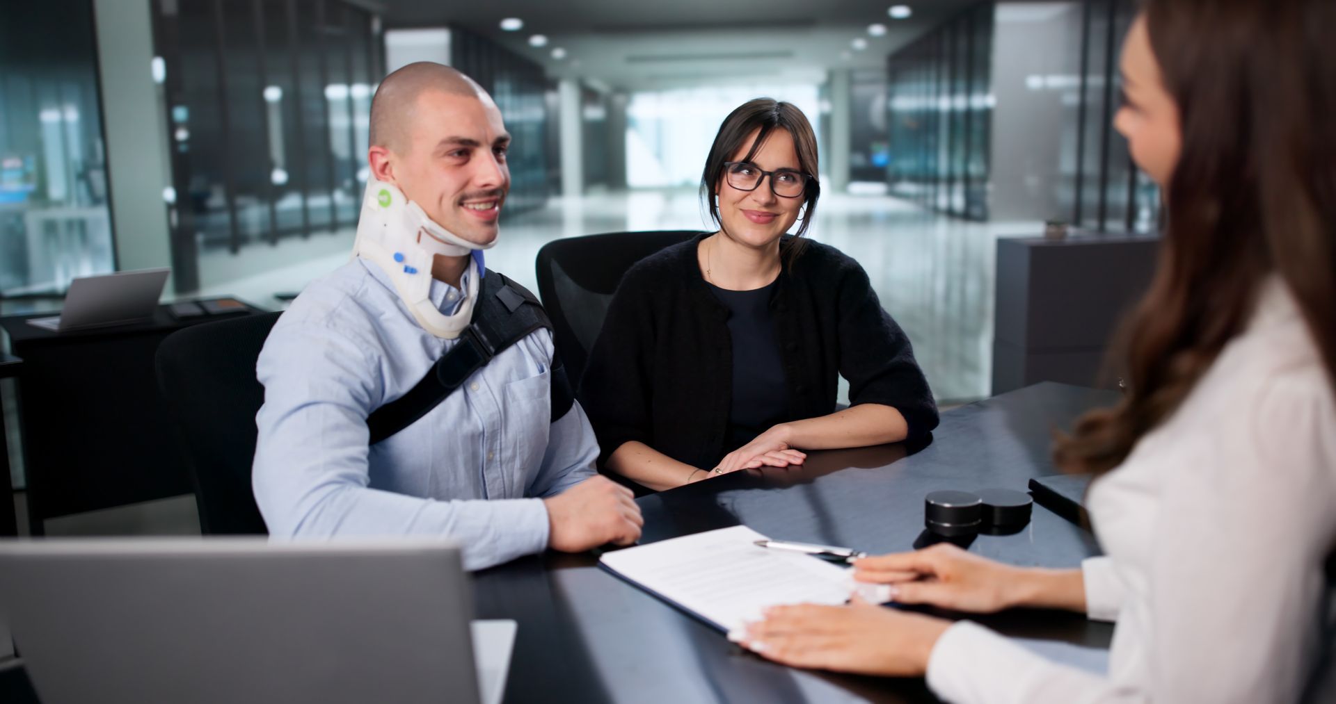 Injured man and wife meet with personal injury lawyer in office.