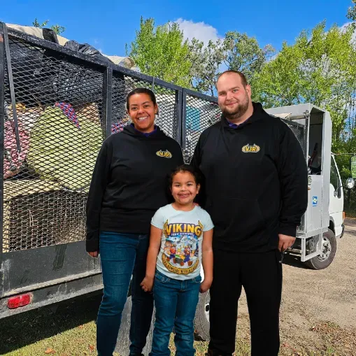 A man and woman standing next to a little girl wearing a viking shirt