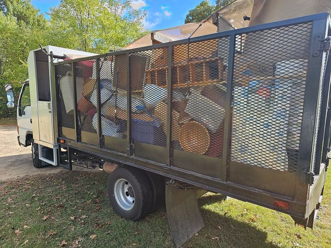 A dump truck filled with junk is parked in the grass.