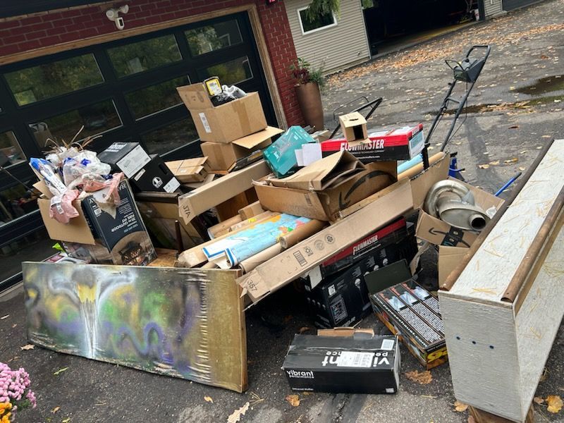 A pile of junk is sitting on the side of the road in front of a garage.