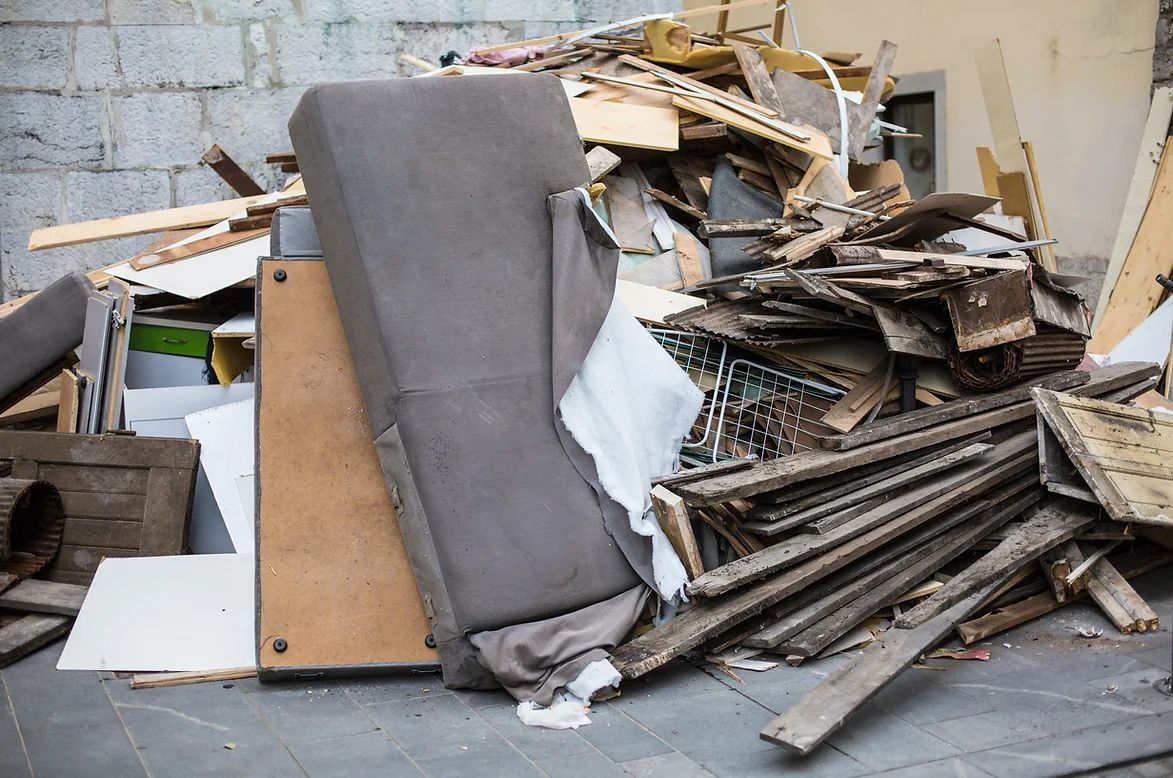 A pile of wood and a couch are sitting on the ground.