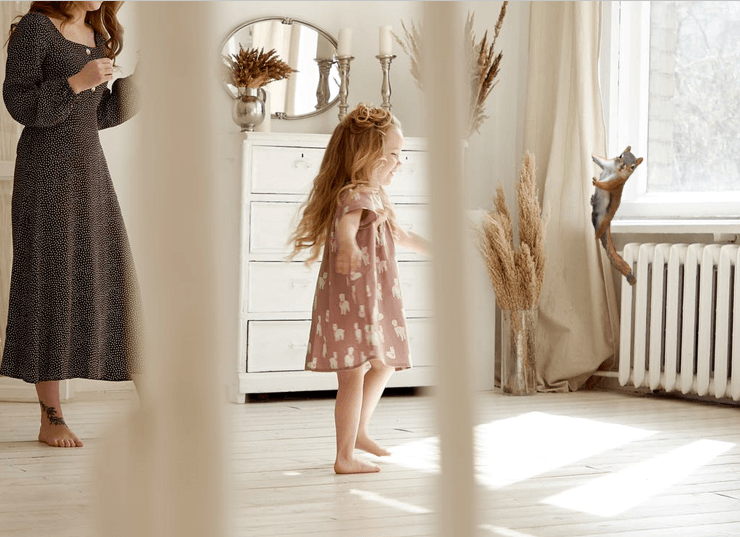 a woman and a little girl are dancing in a living room with a squirrel on curtains