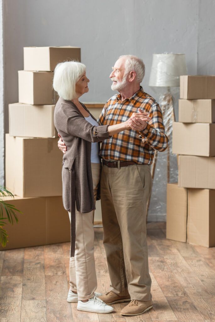 Two people dancing in a room filled with cardboard moving boxes.