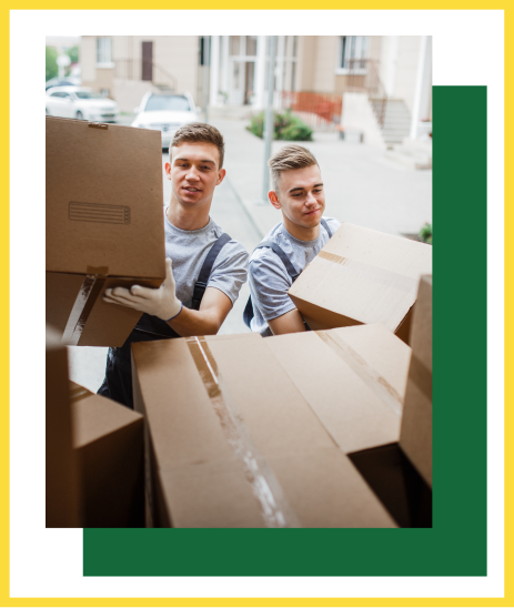 Two workers in uniforms and gloves carrying cardboard boxes outdoors.