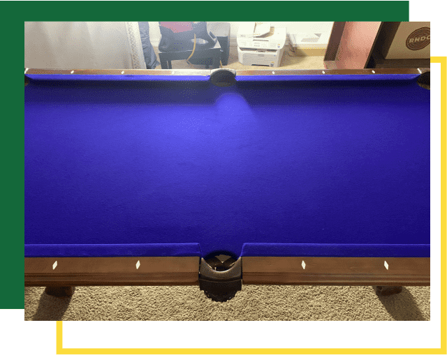 A top-down view of a pool table with a vibrant blue felt surface and wooden rails, framed against a carpeted background.