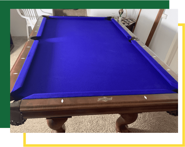 A billiards table with a vibrant blue felt surface and wooden frame, situated in a room with a white chair.