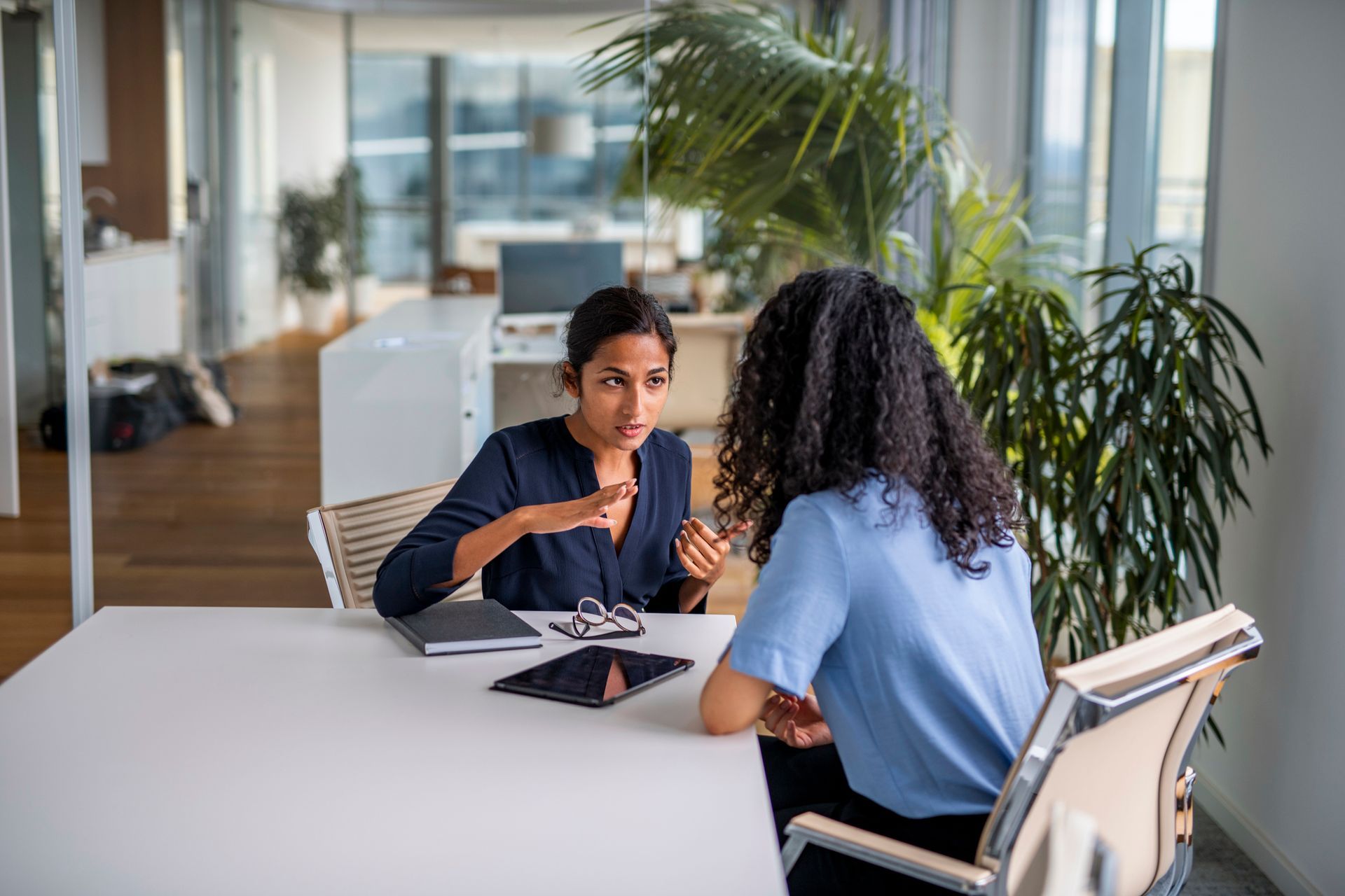 Two women are sitting at a table having a conversation.