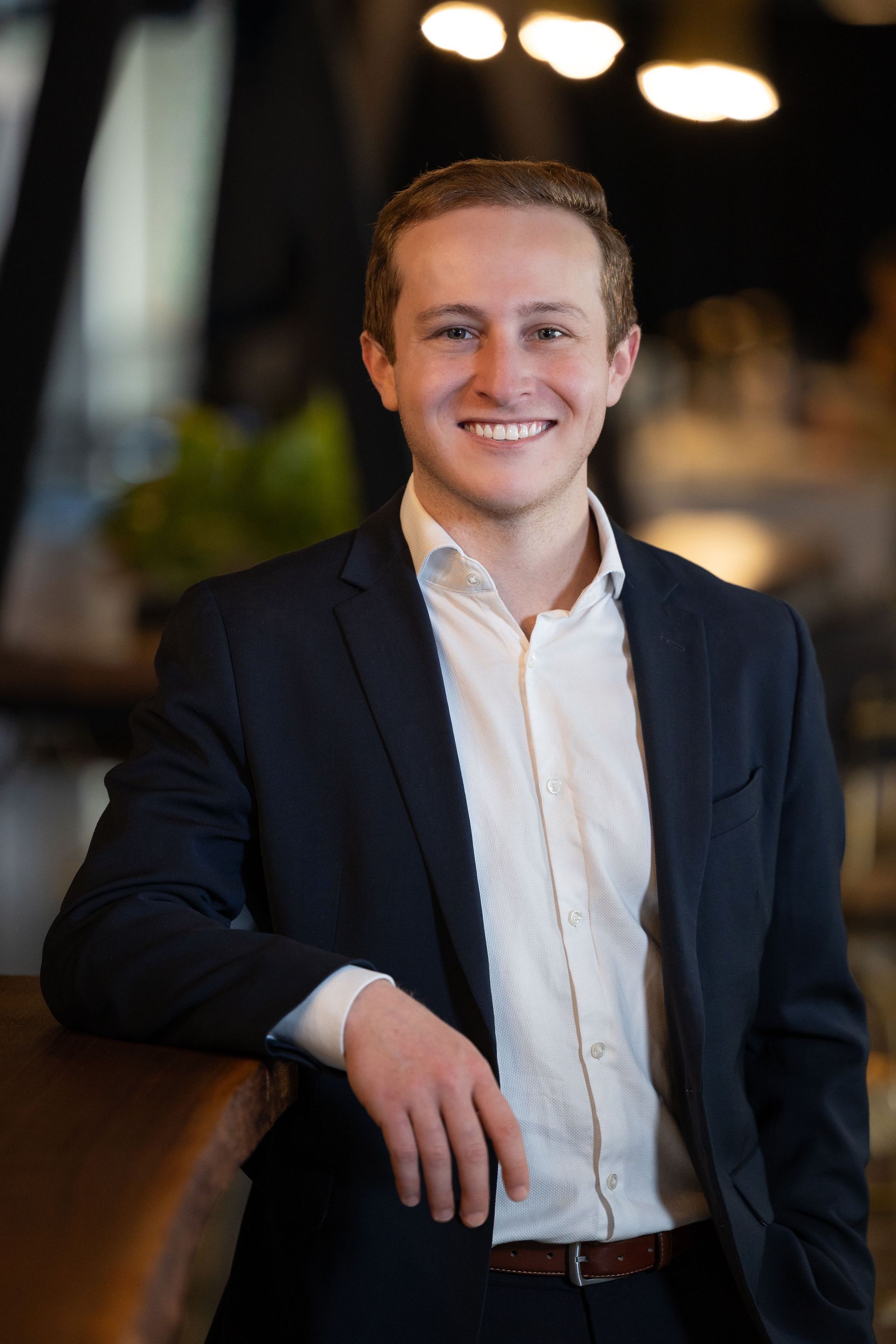 A man with a beard is wearing a blue jacket and a pink shirt.