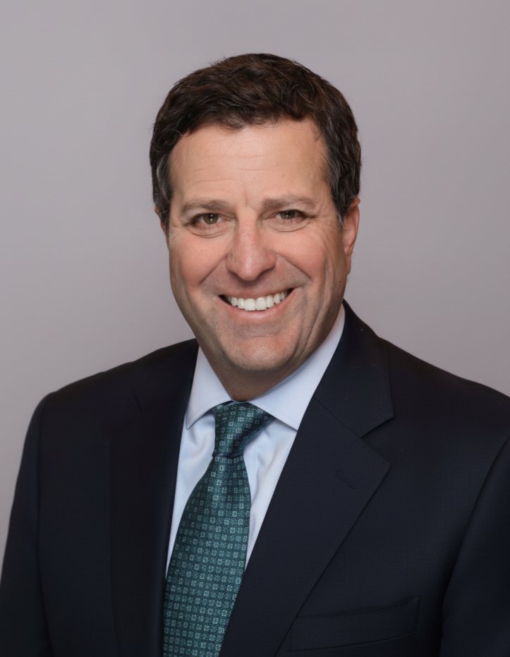 A man in a blue shirt and black pants is standing with his hands in his pockets.