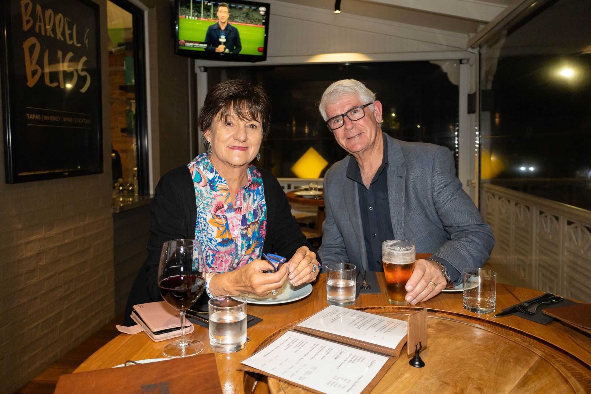 Couple at a restaurant table with drinks and menu, inside, evening.