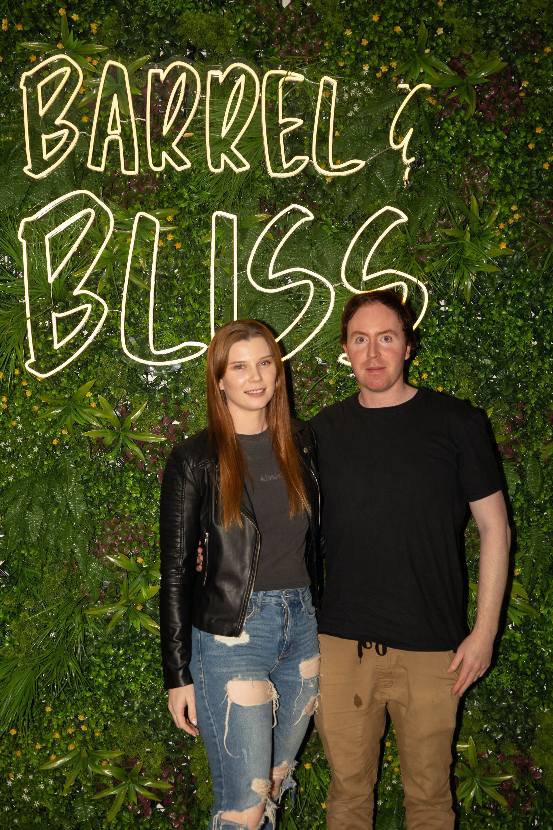 Couple poses in front of a wall sign that reads 
