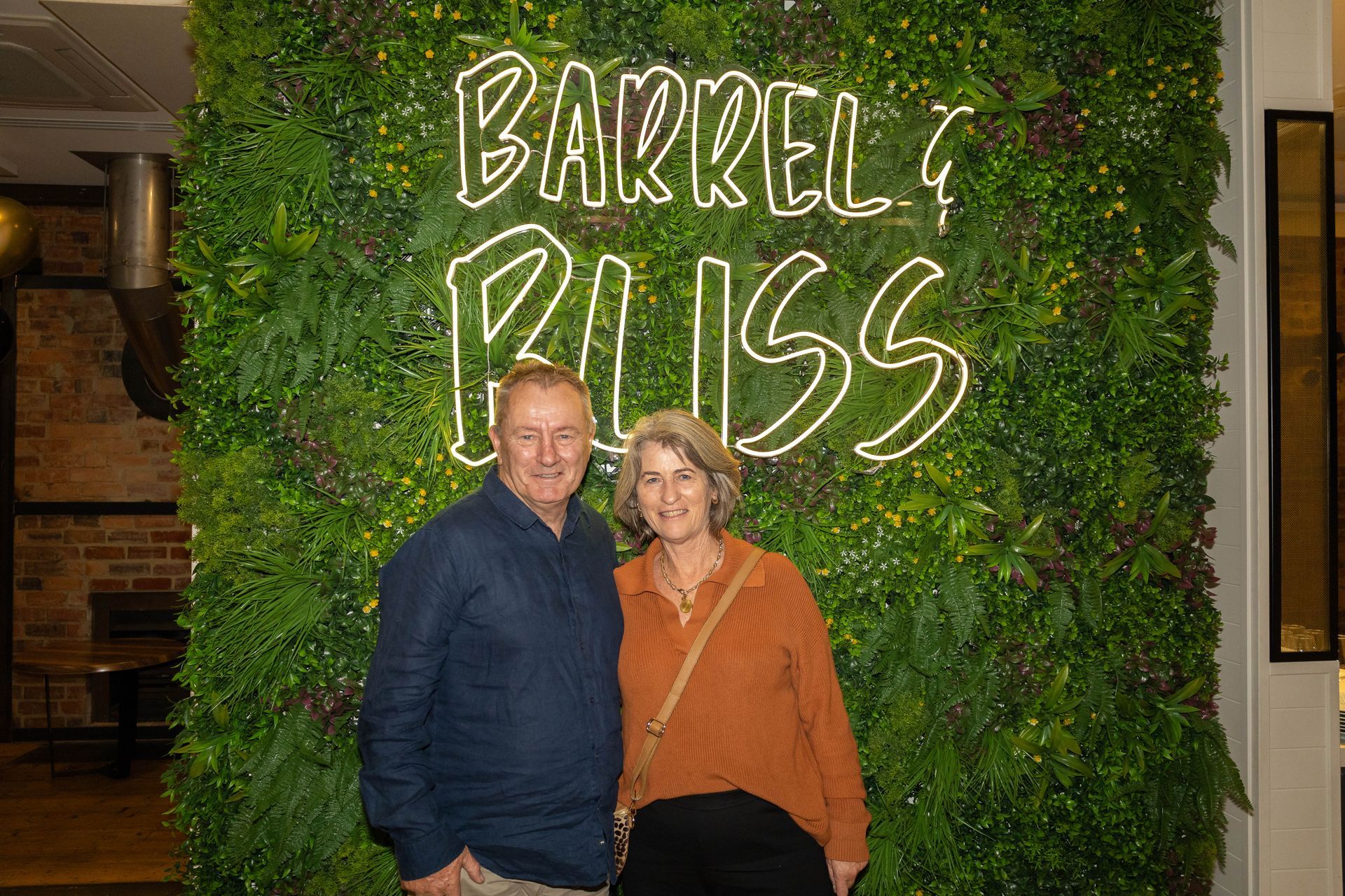 Couple standing in front of a green wall with neon sign 