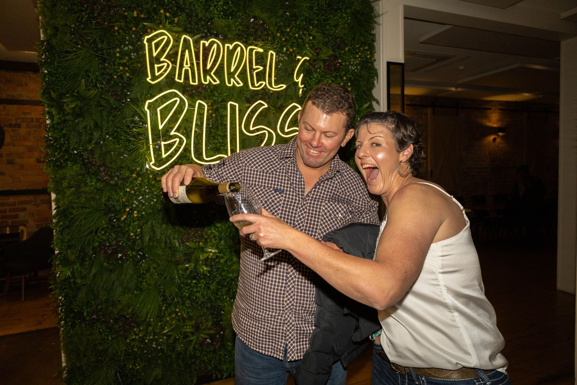 Man pours champagne for a woman, both smiling. 