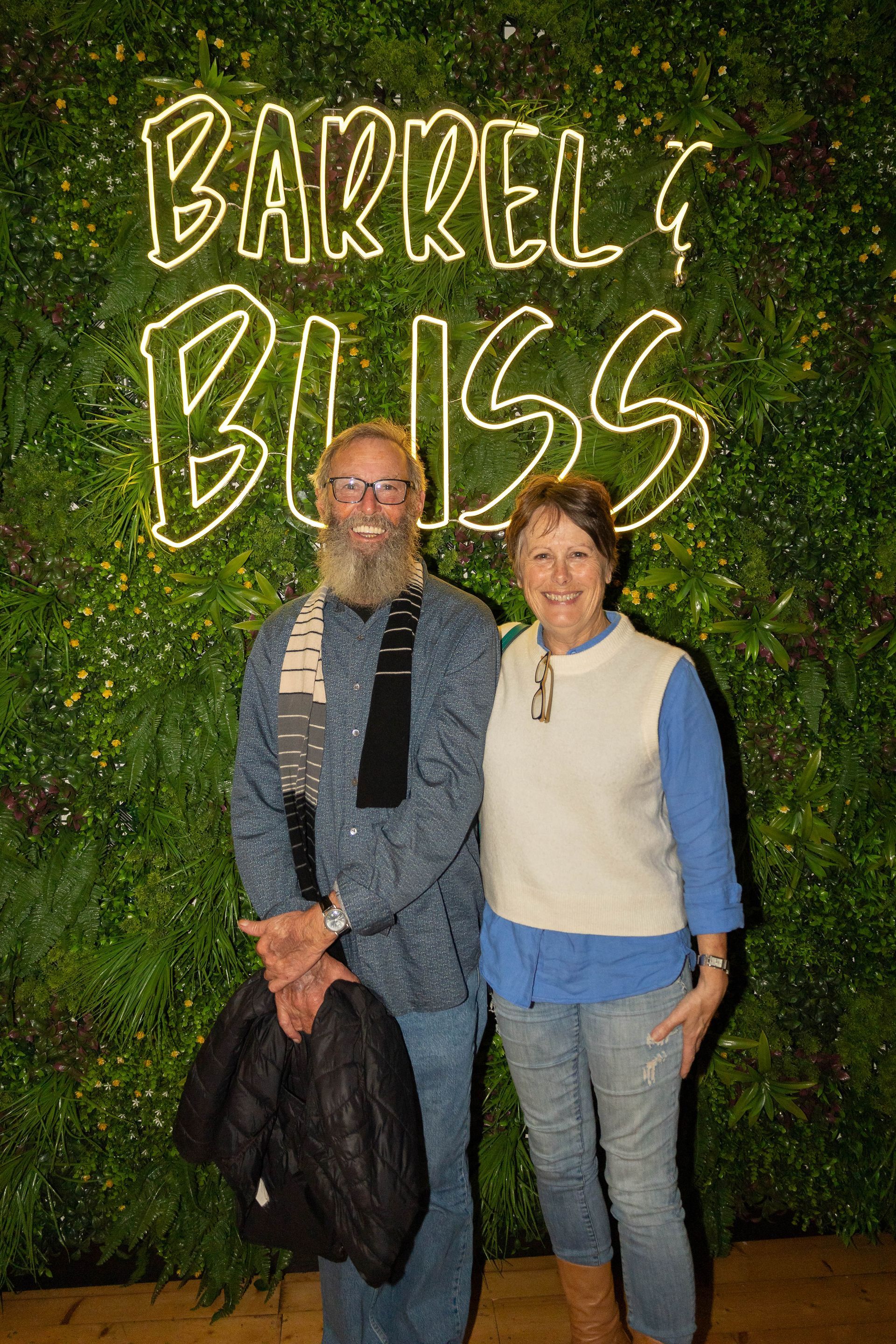 Man with beard and woman pose in front of a 