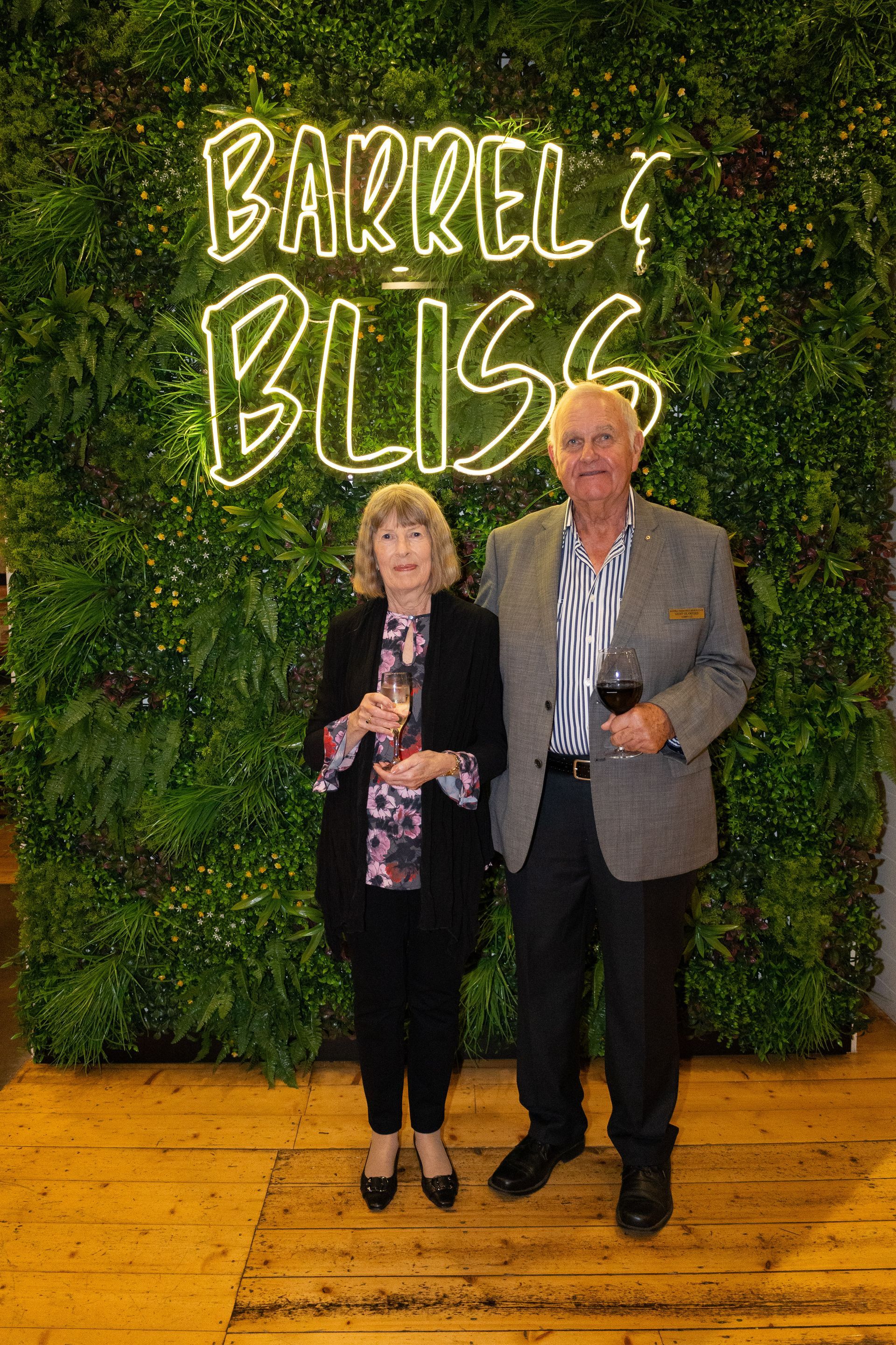 Couple posing in front of a green wall with neon 