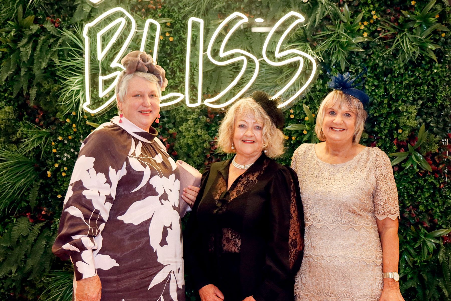 Three women smiling in front of a 