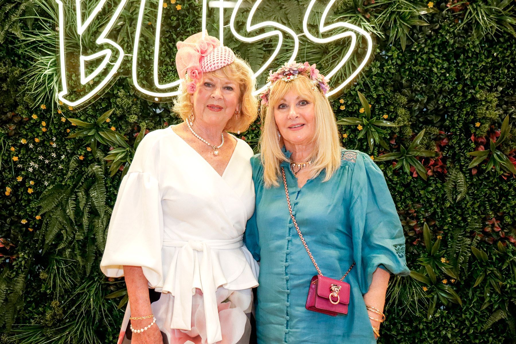 Two women smiling, posing in front of a 