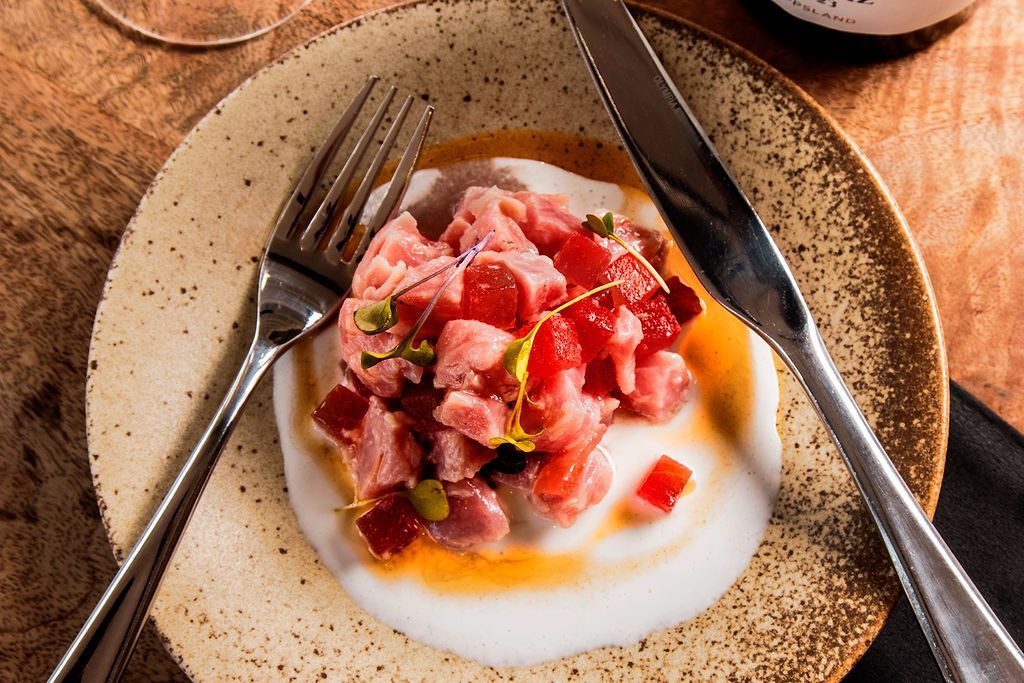 Tuna tartare on a plate with a fork and knife.