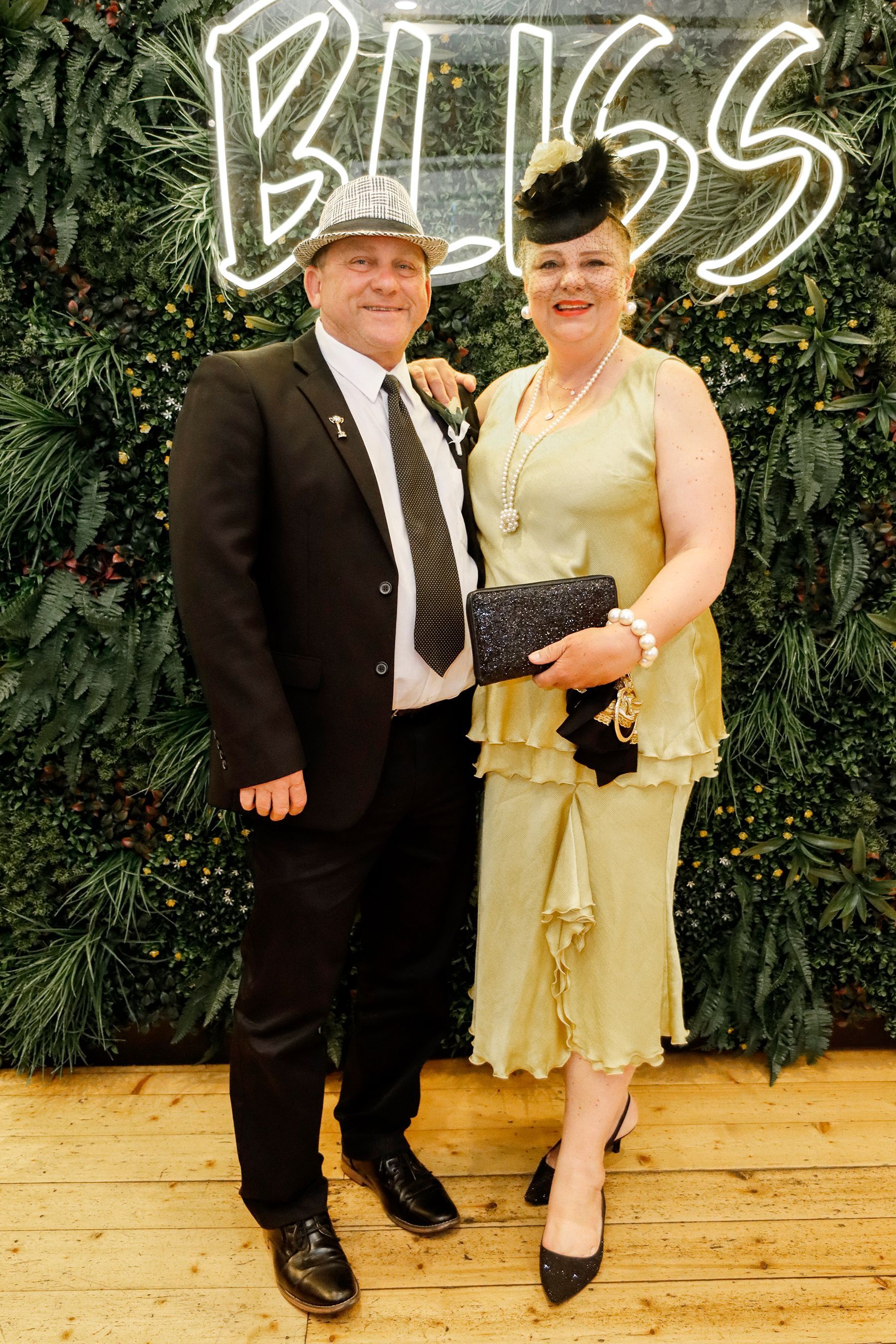 Man and woman in formal attire pose in front of a 