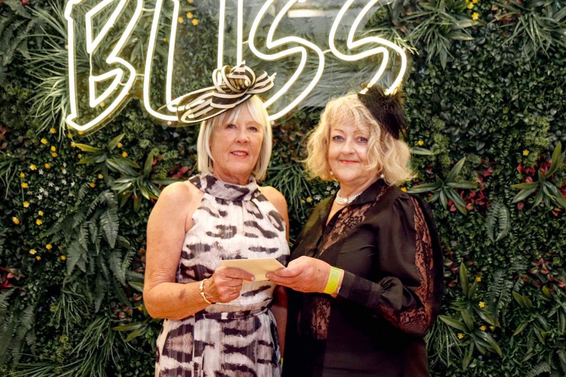 Two women at an event, holding a check, in front of a 