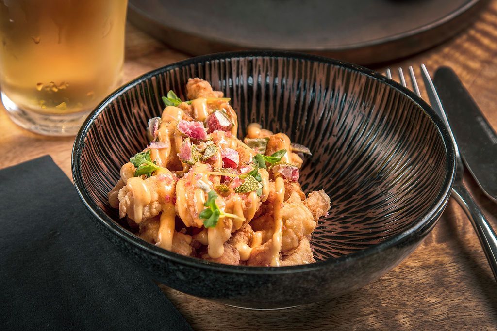 Bowl of crispy cauliflower with pink onions and herbs.