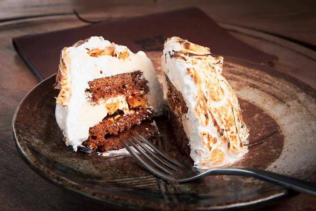 Cake with a browned meringue topping, cut open on a plate with a fork; a menu is in the background.