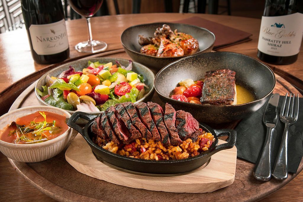 Dinner plate with grilled steak and sides, salad, soup, and wine.
