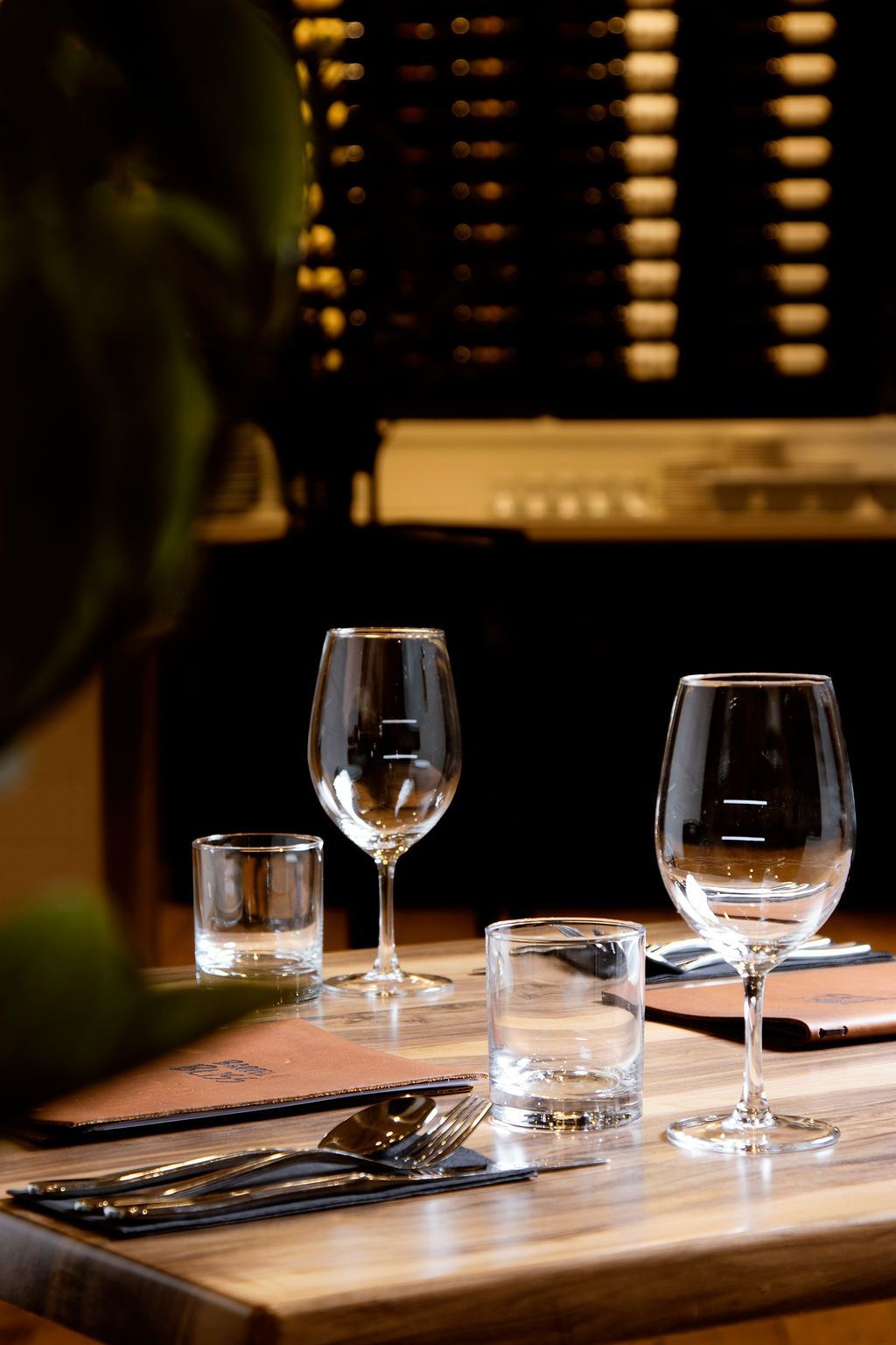 Table setting: two wine glasses, two short tumblers, silverware, and menu.