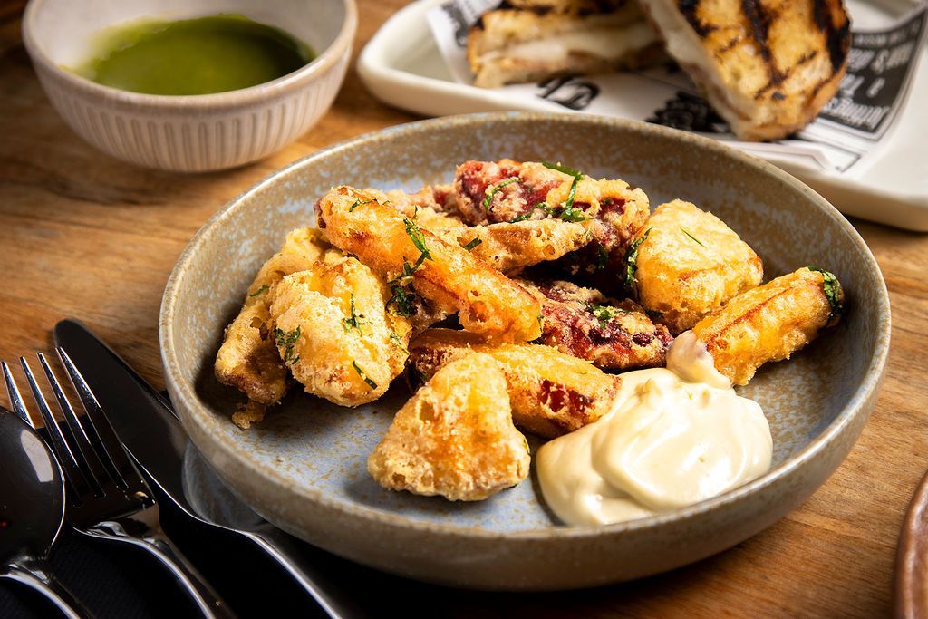 Plate of fried food with dipping sauce; silverware and other dishes nearby.