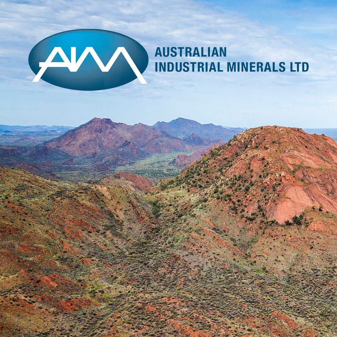 A logo for australian industrial minerals ltd with a mountain in the background